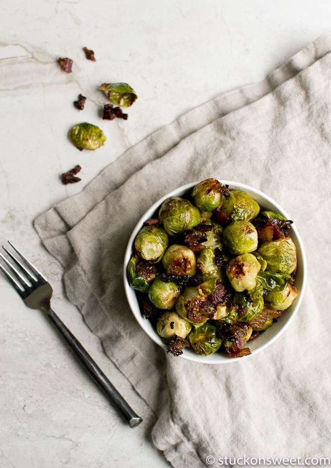 Crispy roasted brussels sprouts with balsamic glaze in a white bowl on linen cloth.