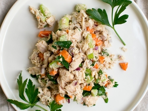 Creamy tuna salad with chopped vegetables on a white plate, garnished with fresh parsley, perfect for healthy lunch recipes.
