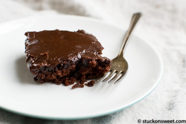 Rich homemade chocolate cake with glossy frosting on a white plate, perfect for dessert or special occasion.