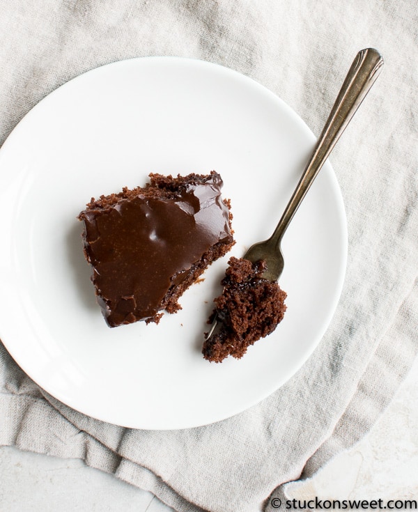 Decadent chocolate fudge pie with glossy chocolate topping on a white plate.