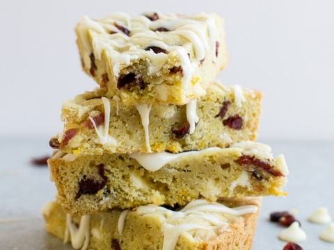 Delicious cranberry white chocolate blondies stacked with drizzle, showcasing soft, chewy texture and sweet flavor, perfect for dessert or snack.