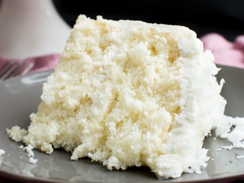 Creamy vanilla cake slice with fluffy moist texture on a grey plate, perfect for birthday celebrations or special occasions.
