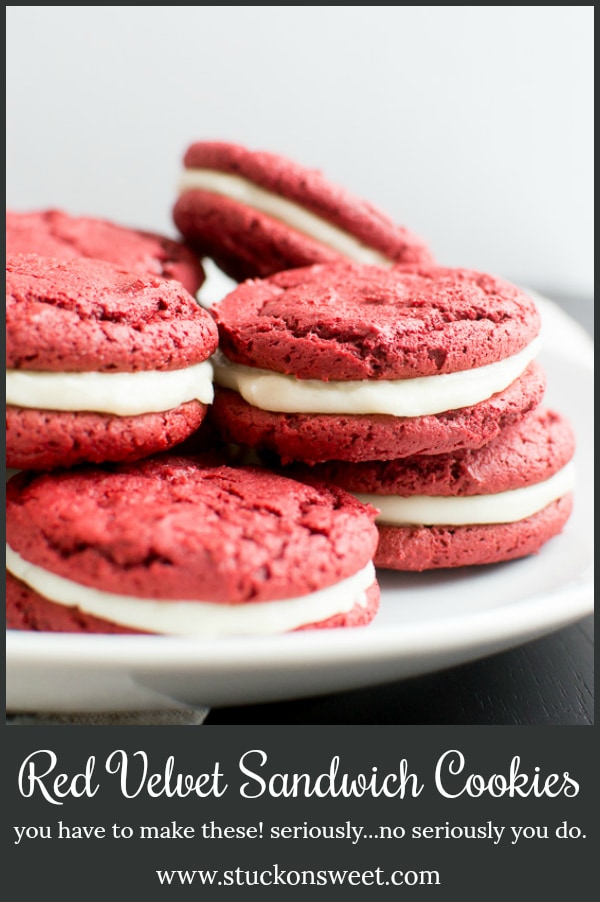 Red velvet sandwich cookies with cream filling on a white plate.