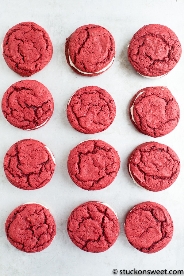Red velvet cookies with cream filling on white surface, delicious homemade sweet treats, perfect for gifting or parties.