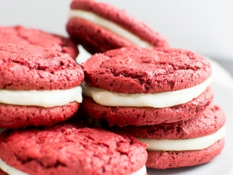 Red velvet cookies with cream cheese filling on a white plate, close-up image.