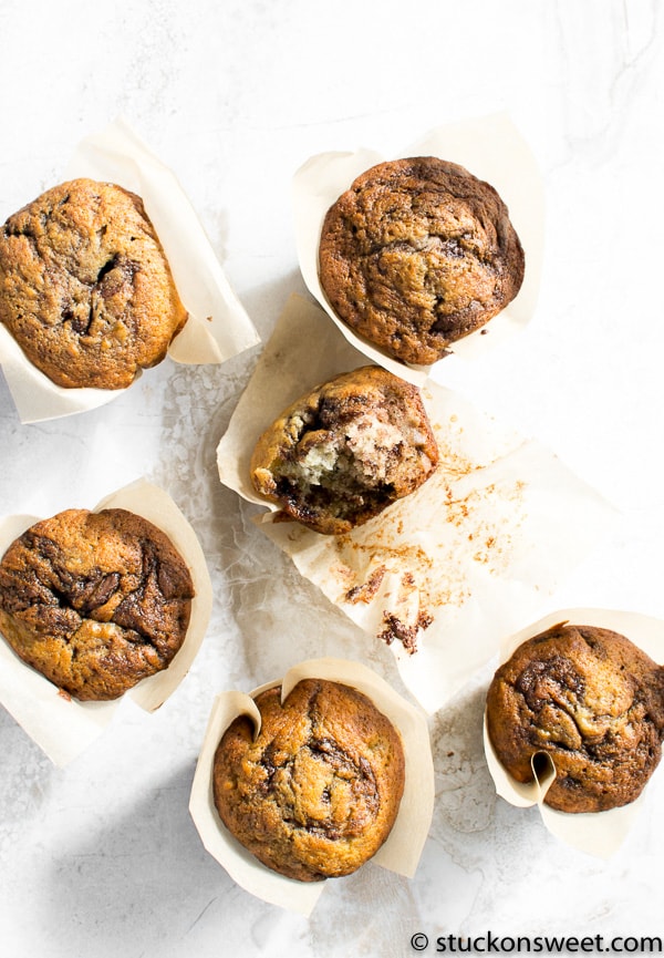 Golden chocolate chip muffins in baking cups on marble surface, homemade baked goods, delicious bakery treats.