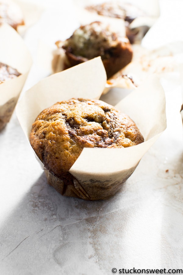 Rich chocolate chip muffin in parchment paper liner, fresh baked and golden brown, perfect for breakfast or snack.