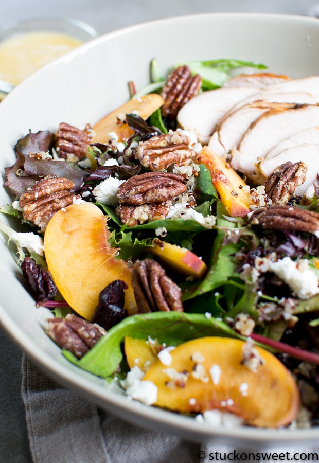 Peach and pecan salad with mixed greens, grilled chicken, and crumbled feta cheese in a white bowl. Fresh, healthy, and delicious salad perfect for lunch or dinner.