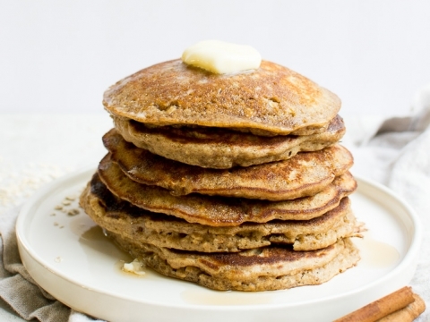 Fluffy homemade banana pancakes topped with butter and cinnamon sticks for breakfast or brunch.
