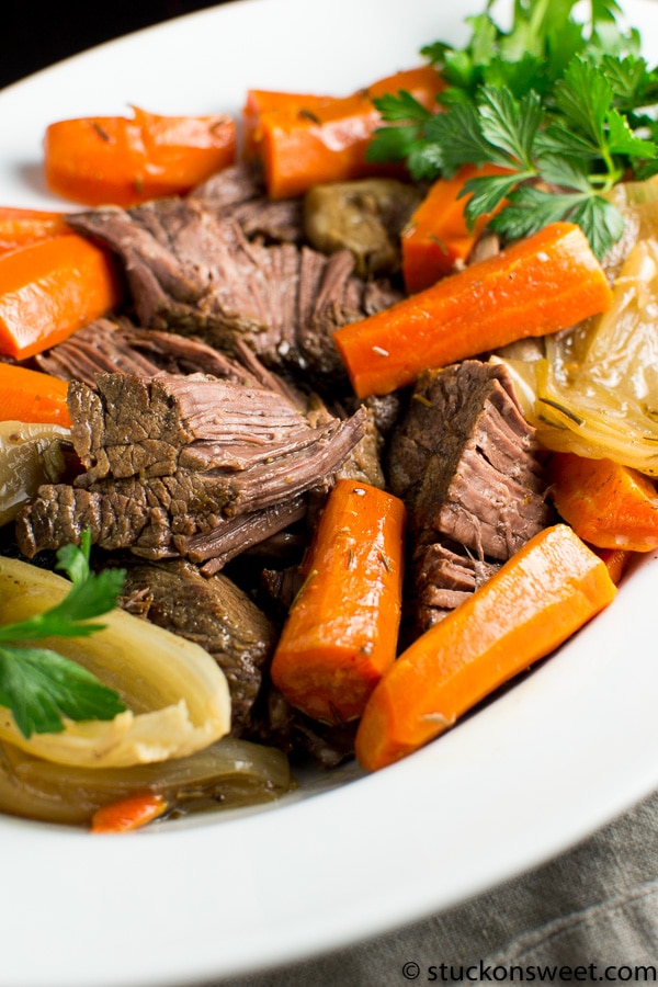 Savory pot roast with tender beef, carrots, celery, and fresh herbs served in a white bowl for a comforting meal. Perfect for family dinners and slow cooker recipes.
