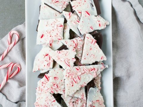 Festive peppermint bark broken into irregular pieces on a white platter for Christmas holiday treats.