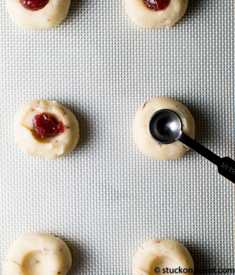 Cream cheese stuffed cherry cookies on baking sheet with cookie scoop ready for baking, showcasing sweet and creamy dessert treats from Stuck On Sweet.