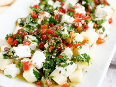 Fresh mozzarella salad with chopped tomatoes, basil, and olive oil on a white platter. Perfect for summer appetizers or side dishes, featuring vibrant flavors and colorful presentation.