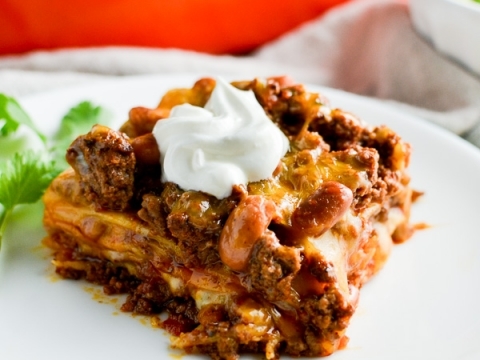 Creamy beef and bean casserole topped with sour cream and fresh cilantro, perfect comfort food for family dinner.