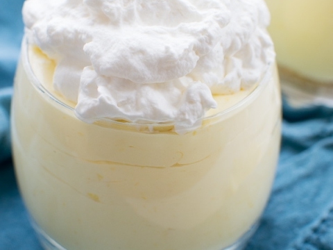 Creamy vanilla pudding topped with whipped cream in a glass dessert cup, perfect for sweet treats and dessert recipes.
