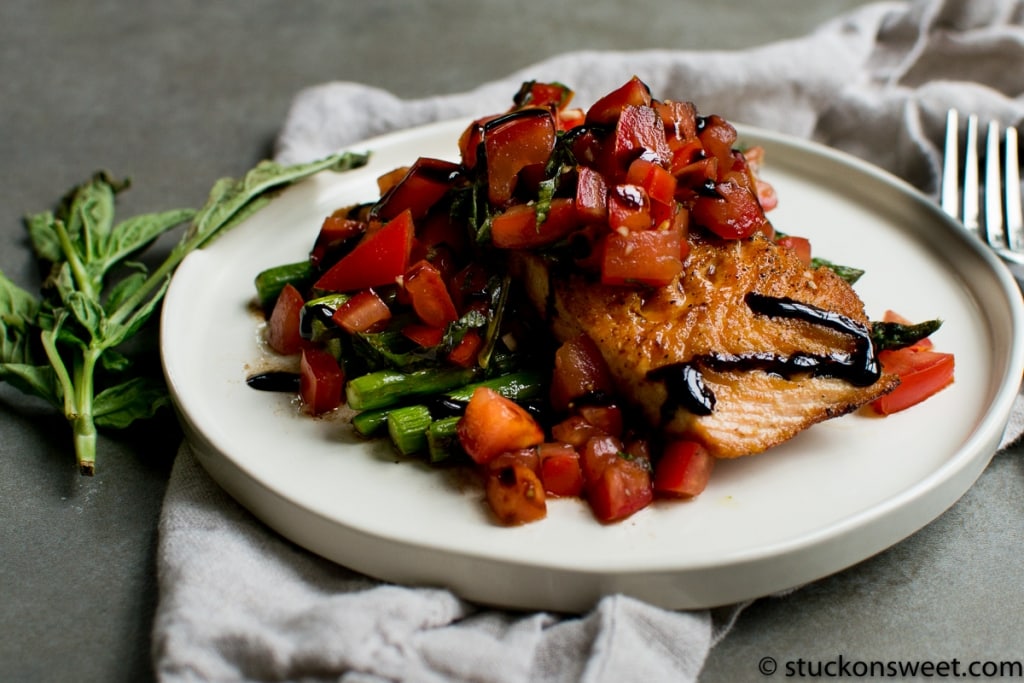 Savory seared fish fillet topped with fresh tomato relish and balsamic glaze on a white plate. Perfect for elegant dinners and seafood lovers.