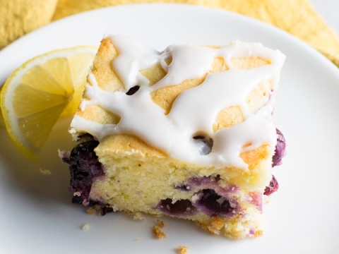 Sweet blueberry lemon upside-down cake with lemon wedge on a white plate.