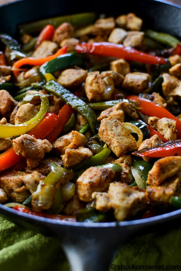 close up view of chicken fajitas with peppers in a cast iron skillet 