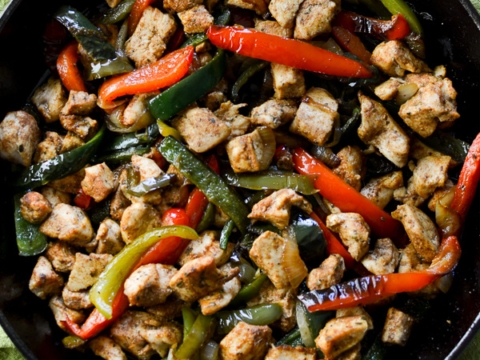 Stir-fried chicken and colorful bell peppers in a black skillet for a healthy, delicious meal. Perfect for dinner, easy to make, and packed with flavor.