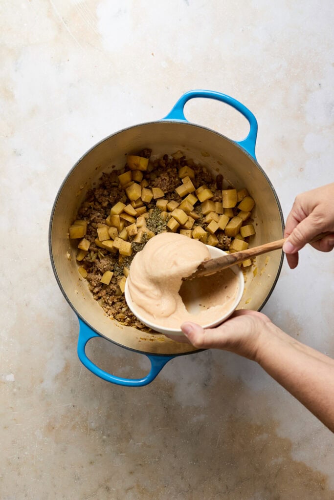Hearty Zuppa Toscana soup with potatoes, sausage, and kale in a blue pot, ready to serve. Perfect comfort food for cold days.