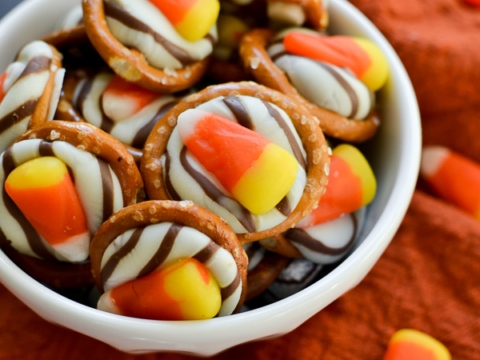 Candy corn pretzel bites with white chocolate drizzle in a white bowl, festive Halloween treat, sweet and salty snack, cute autumn dessert, Stuck On Sweet.