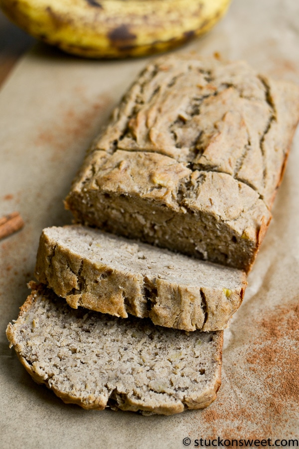 Homemade banana bread with a rustic appearance on parchment paper, showing sliced pieces and a whole loaf, perfect for breakfast or snack.