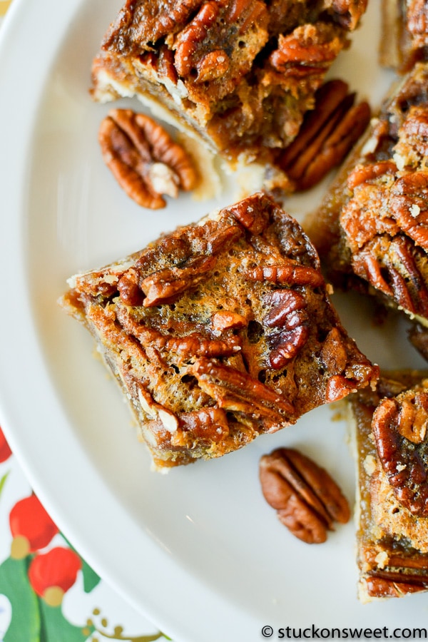 Butterscotch pecan bars with caramel and toasted pecans, close-up view on white plate.