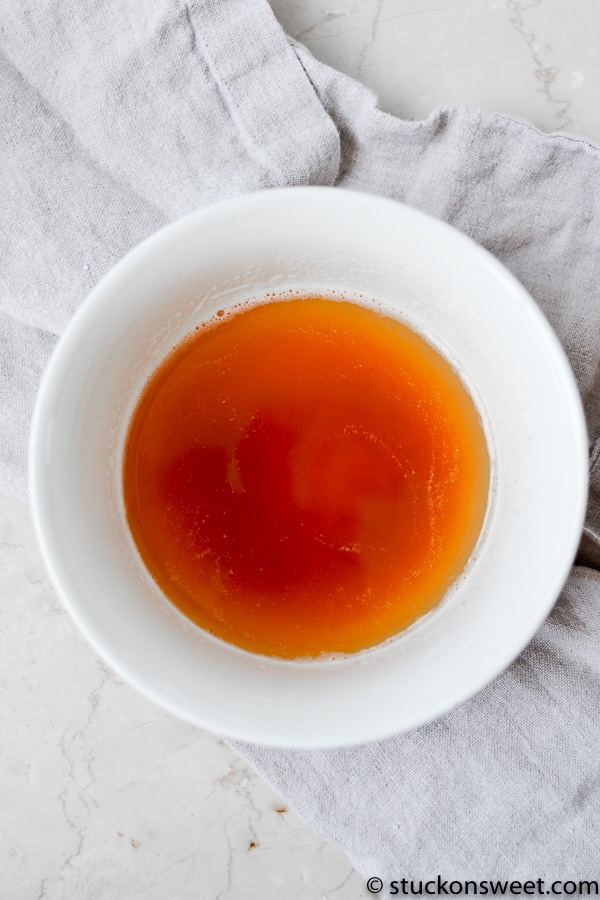Rich caramel sauce in a white bowl on a light surface.