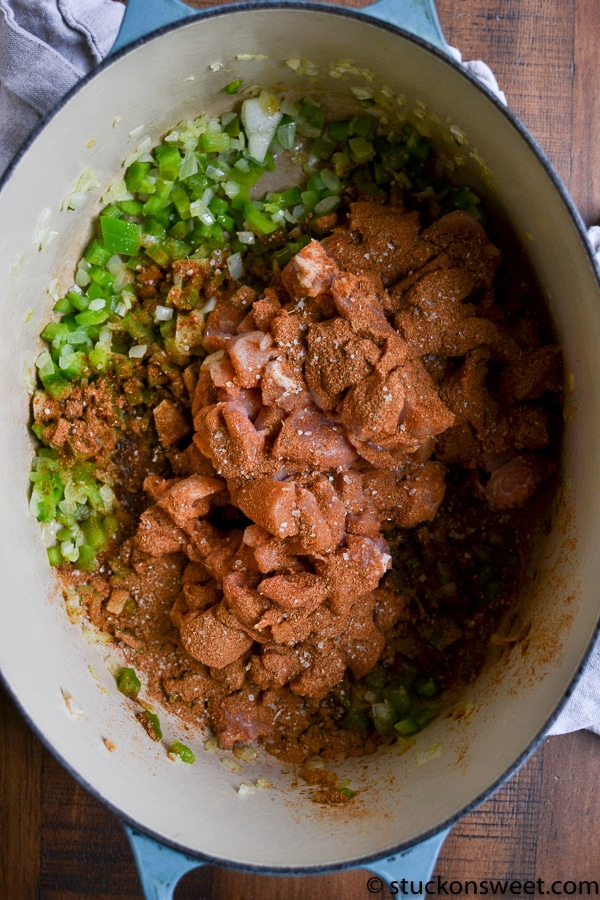Chopped green onions and seasoned raw chicken in a cooking pot for flavorful chicken dishes.