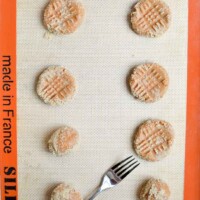 Golden-brown cookies with a textured top, arranged on a baking sheet with a fork; perfect for dessert lovers.