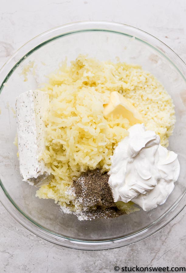 Cream cheese and mashed potatoes in a mixing bowl for cheesy mashed potato recipe.