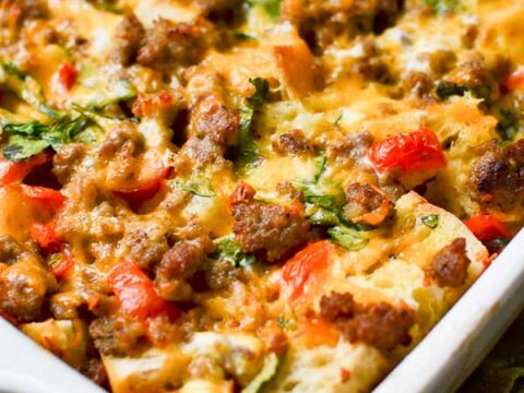 Cheesy baked egg casserole with sausage, vegetables, and melted cheese in a white baking dish. Perfect comfort food for dinner or family gatherings.