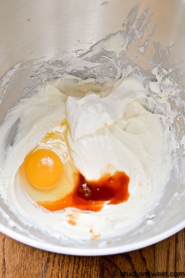 Cream cheese mixture with egg and hot sauce in mixing bowl for baking or cooking recipe.