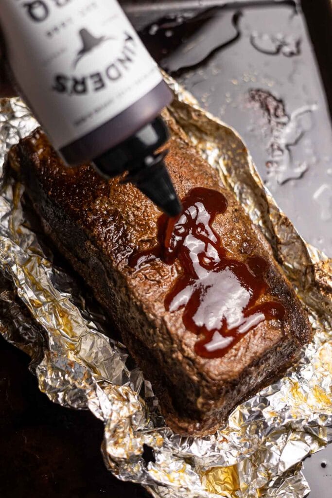Decadent baked chocolate fudge cake with chocolate syrup being drizzled on top.