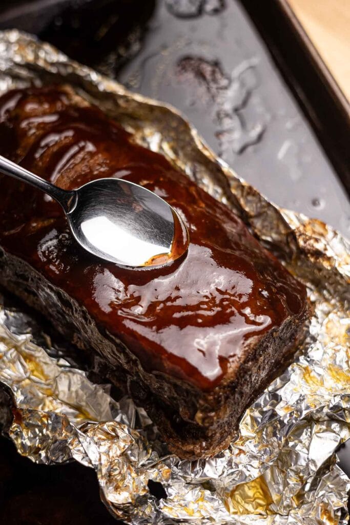 Rich, gooey chocolate glaze on a baked dessert, drizzled over foil-wrapped edges, perfect for decadent desserts and sweet treats.