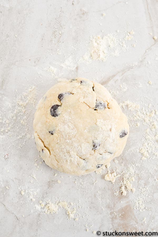 Buttery chocolate chip cookie with flour scattered around on a light surface.