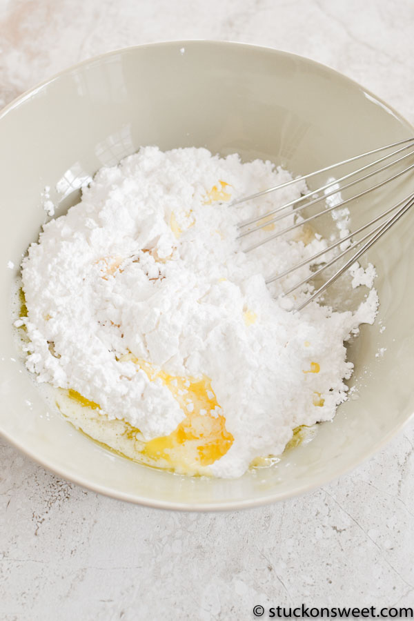 Fine white powdered sugar with butter and eggs in a mixing bowl for baking dessert or confectionery recipes.