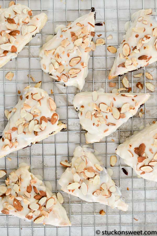 Sweet almond danish pastries with white icing and sliced almonds on a cooling rack.