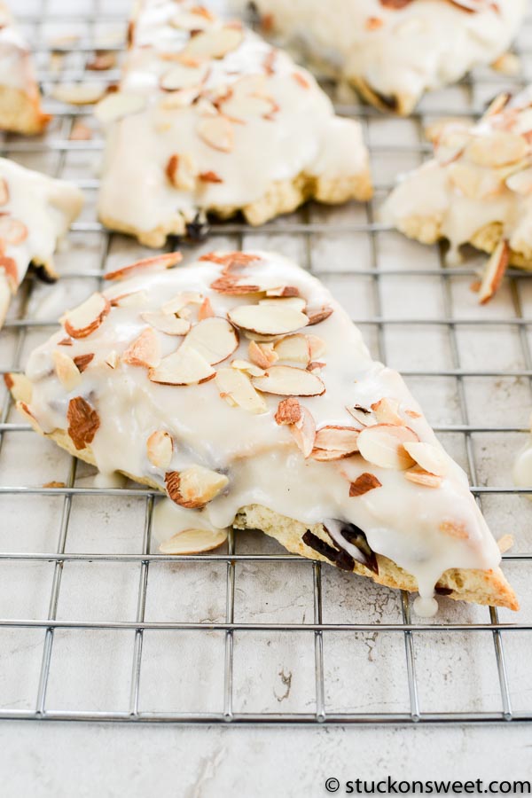 Almond Croissant Danish pastry with white icing and sliced almonds on wire rack.