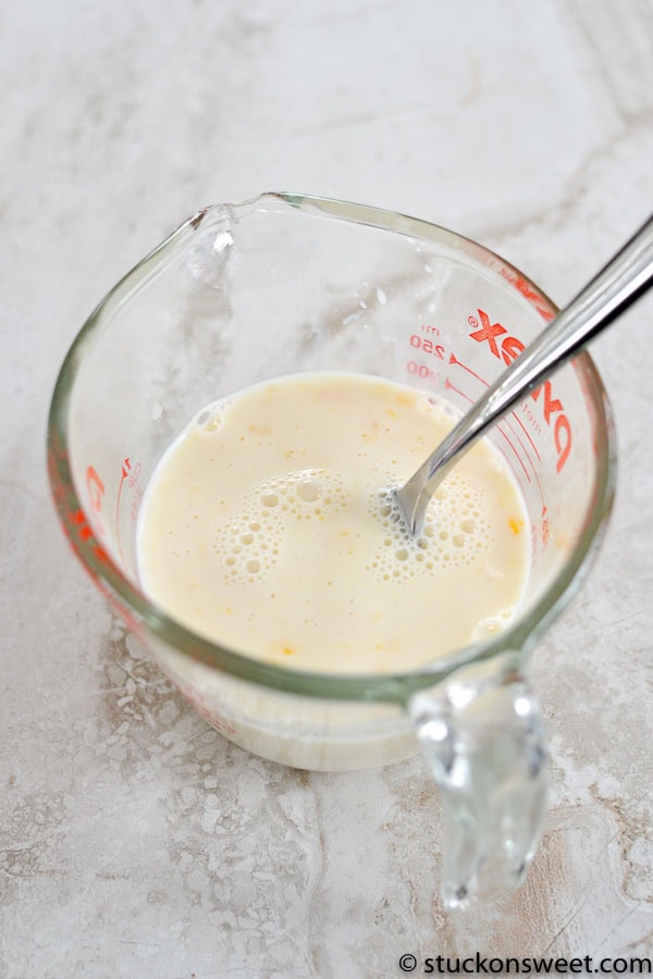 Creamy homemade vanilla custard in a glass measuring cup with a metal spoon; perfect dessert or pie filling.