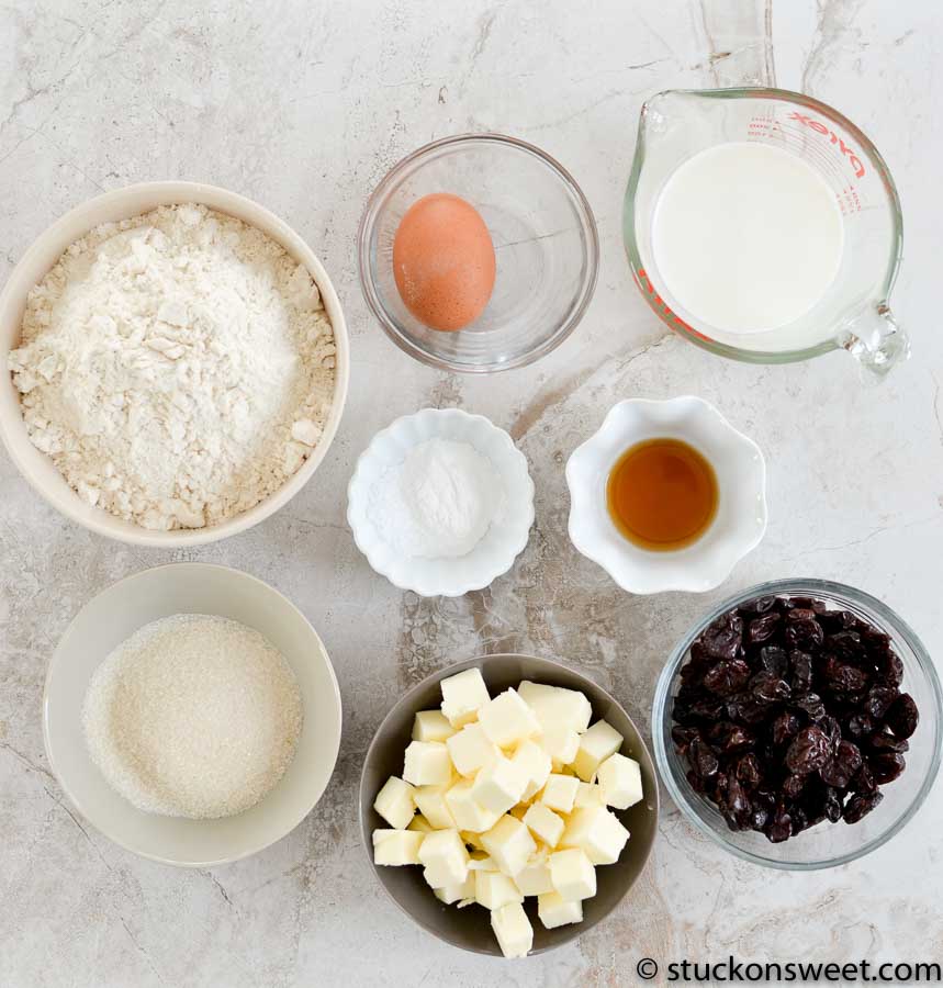 Flour, egg, milk, sugar, vanilla extract, butter, dried cranberries, baking ingredients for baking recipe.