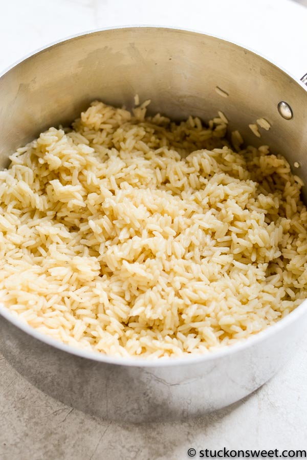 Fluffy cooked rice in a stainless steel pot, perfect for making sweet or savory recipes. A versatile staple in many kitchen dishes, easy to prepare and serve.