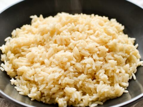Fluffy cooked white rice in a black bowl on a neutral cloth, ideal for recipes or meal prep.