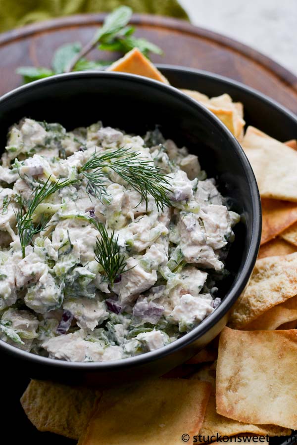 Tzatziki chicken salad in black bowl with fresh dill on top