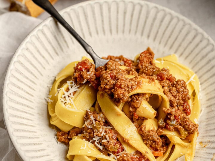 Creamy homemade spaghetti baghetti with meat sauce served in a white bowl, with toasted garlic bread on the side, perfect for cozy Italian dinner.