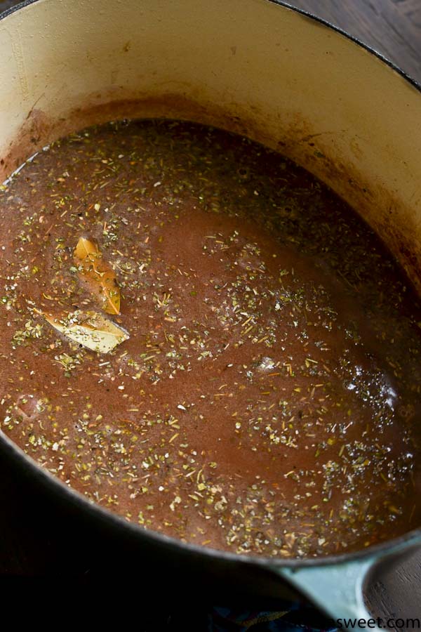 Aromatic seasoned broth with herbs and spices in a black pot suitable for cooking or making savory dishes.
