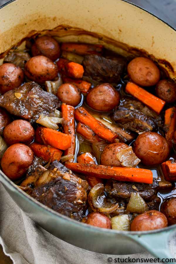 Tender beef stew with baby potatoes, carrots, and onions cooking in a savory broth in a large pot, perfect for comforting home-cooked meals.
