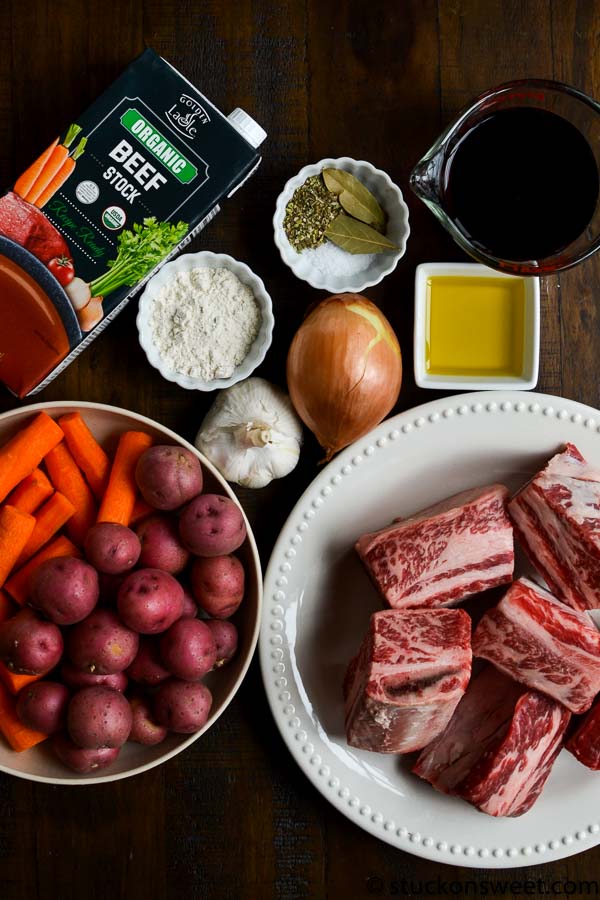 Organic beef stock carton with fresh vegetables and seasonings for hearty beef stew preparation.