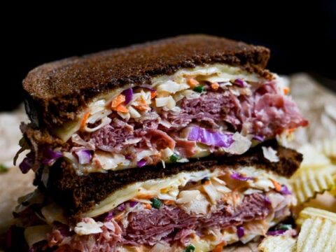 Crispy fried bologna sandwich with coleslaw on dark background, close-up.