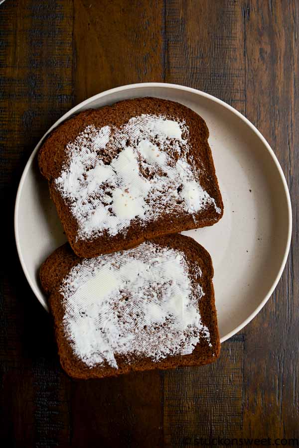 Soft chocolate bread slices with butter, dusted with powdered sugar on a white plate, perfect for breakfast or dessert, from Stuck On Sweet.
